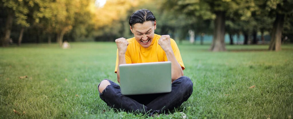Man Sitting on a Green Grass Field Optimising his Businesses Website for SEO.