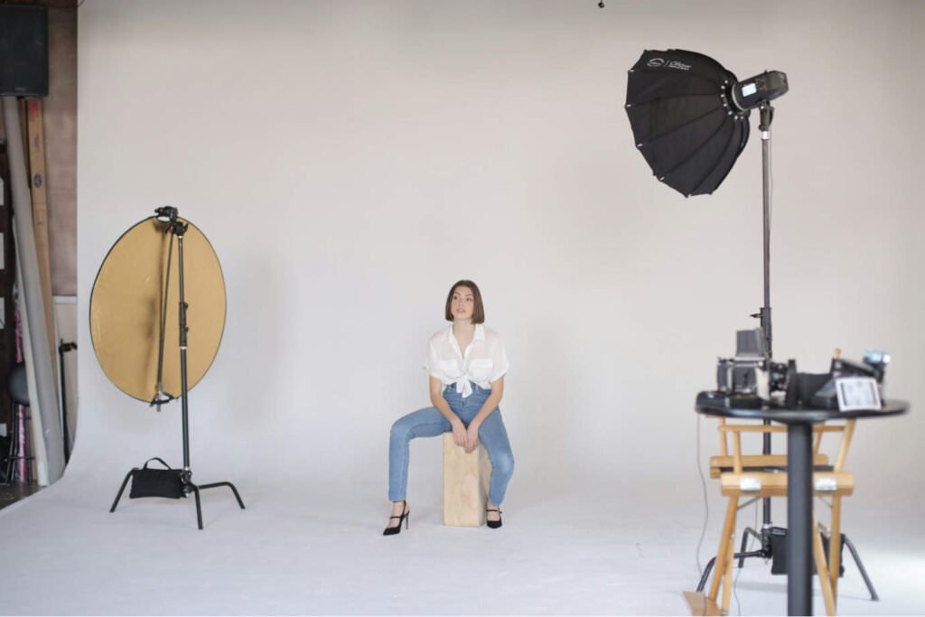 A professional photography studio with a lady model in the middle of the frame.